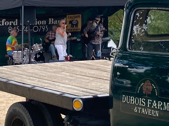 A flat bed DuBois Farm & Tavern parked in front of a stage with a band playing.